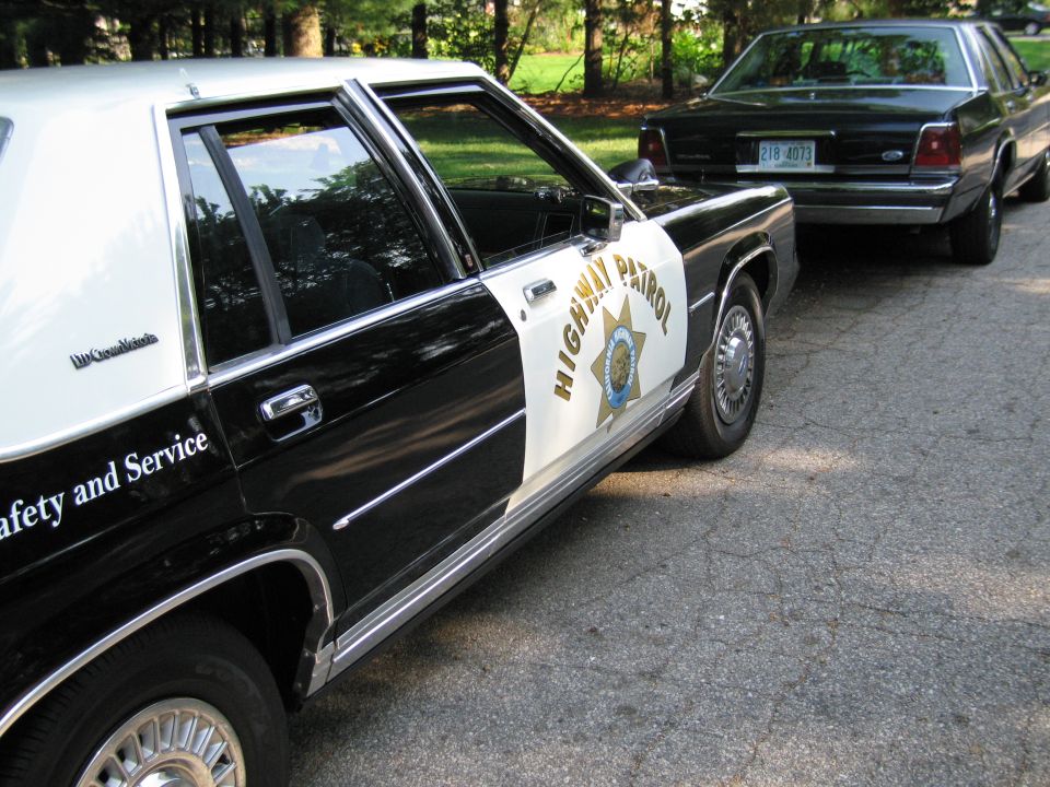Close view of black-and-white HIGHWAY PATROL sedan door reading Safety and Service