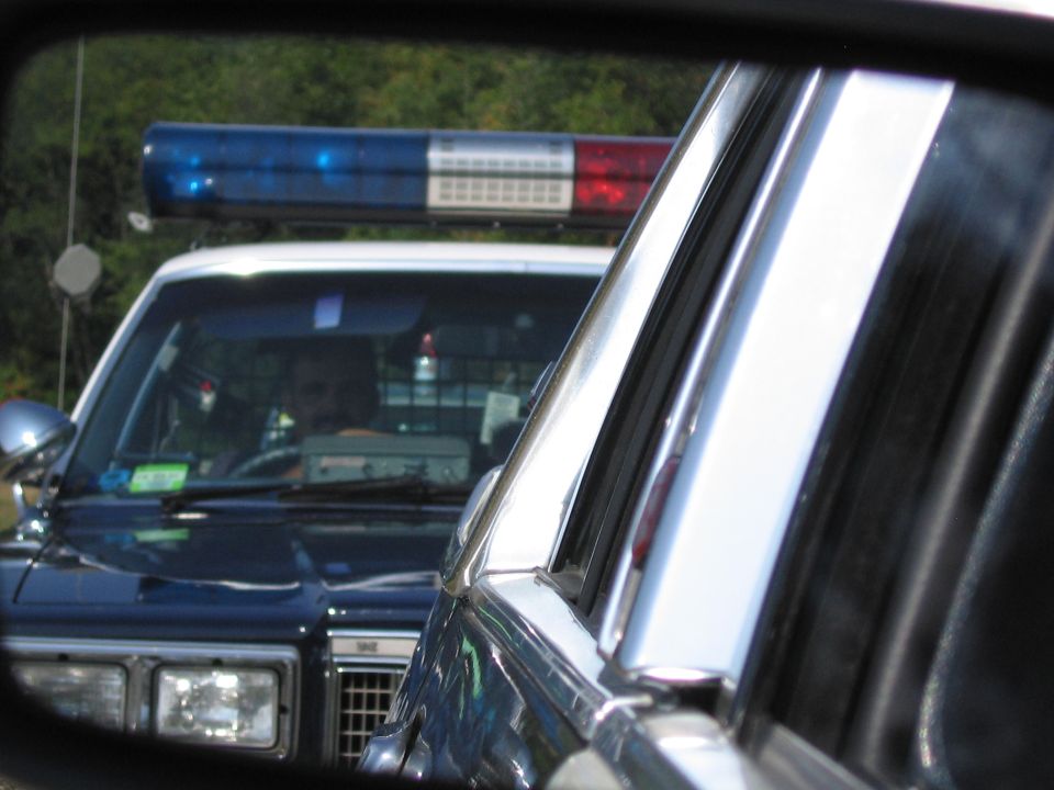 Police car roof lightbar and grille seen through a vehicle window