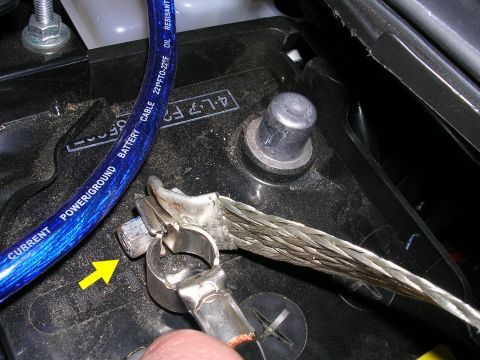 2007 Mazda 3 - A close-up view of a car battery terminal connection, showing a blue power cable and a braided ground strap.