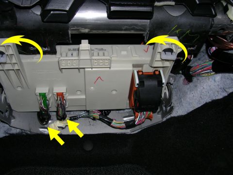 2007 Mazda 3 - Close-up of a vehicle's fuse box and wiring harness, with yellow arrows indicating specific connection points and clips.