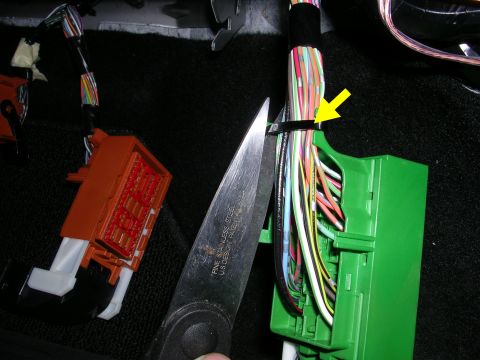 2007 Mazda 3 - A close-up view of a vehicle's wiring harness, with a zip tie being cut.