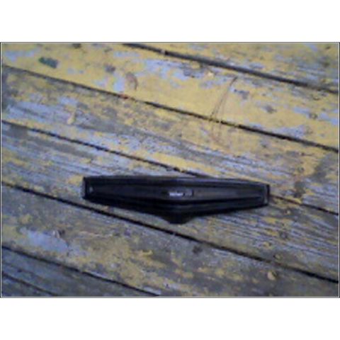 1973 Ford Ranchero - A black car part rests on weathered wooden planks, its exact make and model not identifiable from the image.