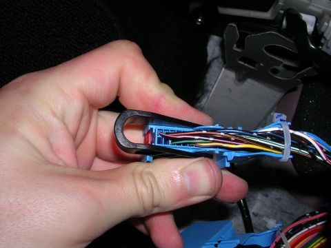 2007 Mazda 3 - A hand disconnects a complex wiring harness connector, revealing numerous colored wires.