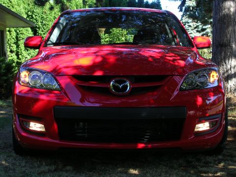 2007 Mazda 3 - Frontal view of a red 2007 Mazda 3, showing its grille, headlights, and fog lights.
