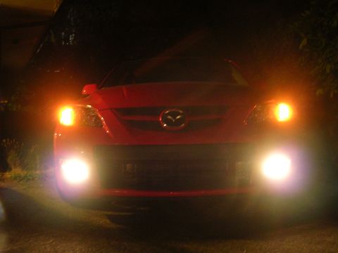 2007 Mazda 3 - A red Mazda 3 is parked at night with its lights illuminated.