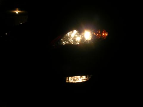 2007 Mazda 3 - The front of a car is visible in the dark, with the headlight and fog light illuminated.