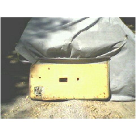 1973 Ford Ranchero - Unidentified yellow car part with a cutout, resting on gravel and covered by a tarp.