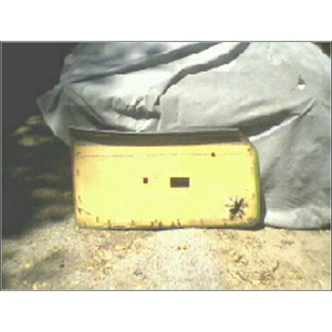 1973 Ford Ranchero - A yellow car part with two rectangular holes sits on the ground, partially covered by a gray tarp.