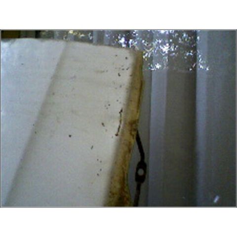 1973 Ford Ranchero - A close-up view of a dirty, off-white panel with a black wire attached to its edge, possibly from a vehicle's interior.