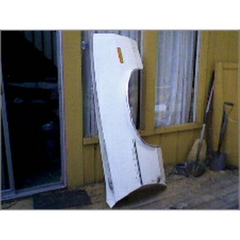 1973 Ford Ranchero - A white fender with an amber marker light is leaning against a yellow building, with shovels nearby.