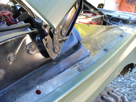 1978 Ford Bronco - Close-up view of a vehicle's engine bay, revealing the hood hinges and surrounding metalwork, with visible signs of damage.