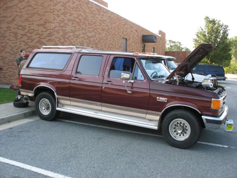 1995 Ford C-150 (Centurion Conversions) - A maroon Ford F-250 Centurion conversion van is parked with its hood up, next to another van.