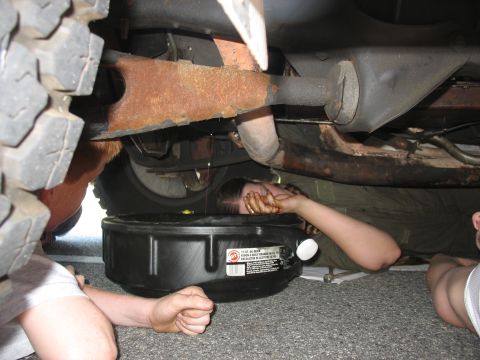 1995 Ford C-150 (Centurion Conversions) - Changing the oil on a vehicle, with a drain pan positioned underneath.