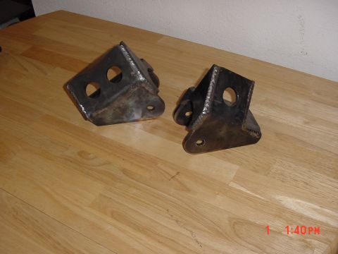 1992 Toyota Tacoma - Two custom metal brackets sit on a wooden surface.
