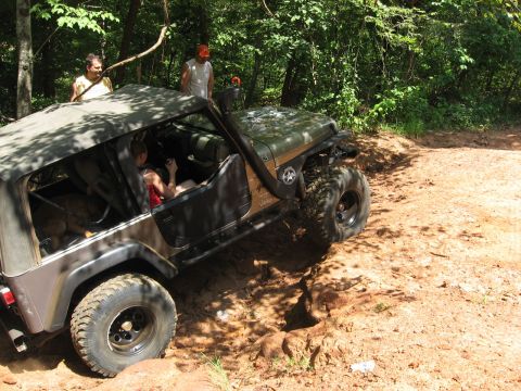 2004 Jeep Wrangler - A Jeep Wrangler navigates a challenging dirt trail with two people watching.