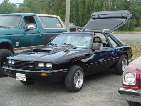 1996 Ford Bronco - A black Ford Capri with flame decals and an open t-top is parked next to a green Ford Bronco.