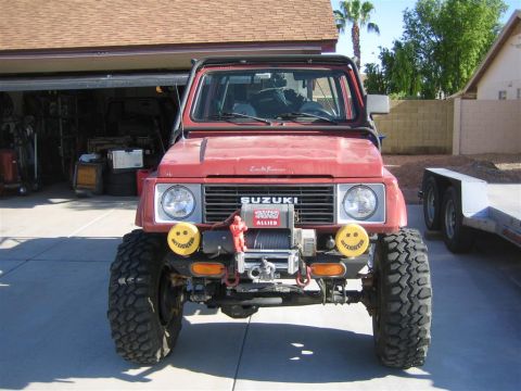 1987 Suzuki Samurai - This 1987 Suzuki Samurai features a prominent winch and custom exo cage, ready for off-road adventures.