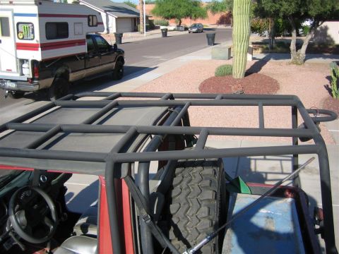 1987 Suzuki Samurai - The photo shows the interior of a modified off-road vehicle with a prominent roll cage, with a pickup truck and camper in the background.