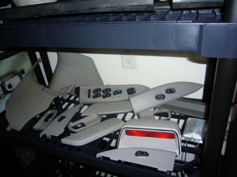 2000 Ford Crown Victoria - Various interior car parts, including door panels and window switches, are displayed on shelves.