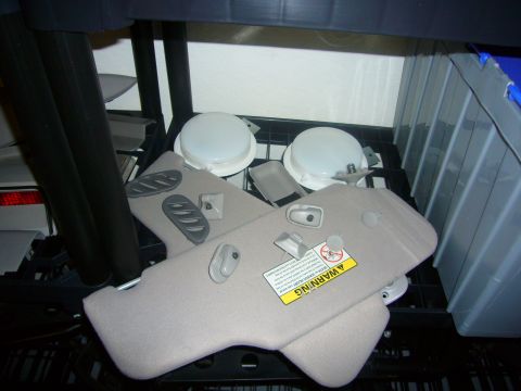 2000 Ford Crown Victoria - Various car interior parts are piled on a shelf, including sun visors and dome lights.
