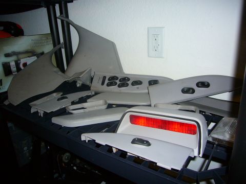 2000 Ford Crown Victoria - Various disassembled interior car components are neatly organized on shelving units.