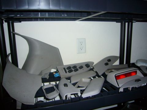 2000 Ford Crown Victoria - Various interior car parts are organized on a shelf, suggesting a disassembled vehicle or spare parts inventory.