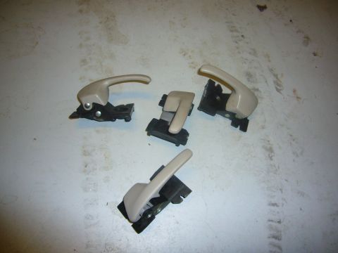 2000 Ford Crown Victoria - Set of four interior door handles, likely for a Ford Crown Victoria, displayed on a workbench.