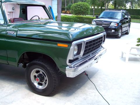 1978 Ford Bronco - A green 1978 Ford Bronco is parked on a driveway, with a black Lincoln Navigator in the background.