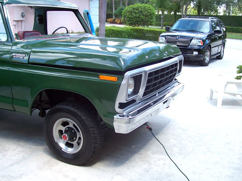 Green 1978 Ford Bronco parked on driveway, with a black Lincoln Navigator behind it