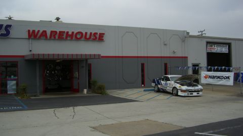 1990 Ford Probe - Race car with hood open parked in front of a warehouse.