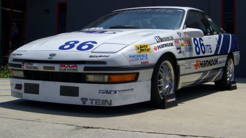 1990 Ford Probe - This 1990 Ford Probe is adorned with numerous sponsor decals and racing numbers, indicating its use in competitive motorsport.