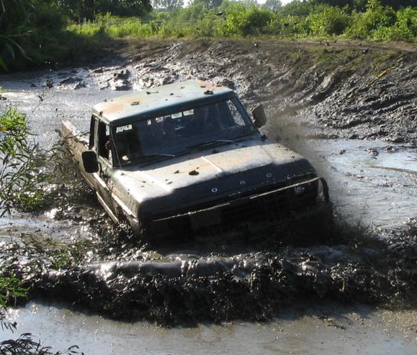 Ford pickup truck driving through a mud pit, splashing water