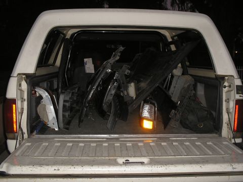 1990 Ford Bronco - A white pickup truck's bed is filled with various car parts, suggesting a repair or restoration project.