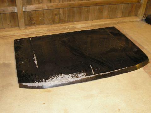 1990 Ford Bronco - A detached car hood lies on the floor, showing signs of wear and tear along its edges.