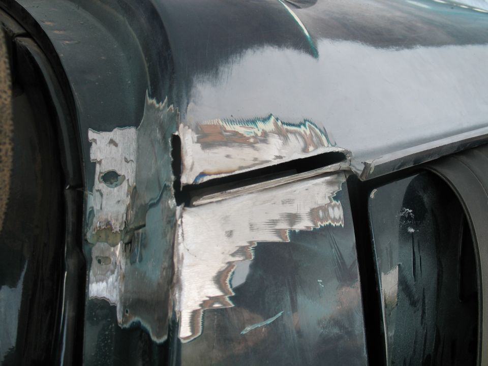 Close-up of bare metal and peeling dark green paint at a body seam on a Ford Bronco