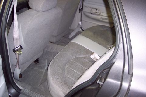 2001 Ford Crown Victoria - The interior of a car's back seat shows gray cloth upholstery and seatbelts.
