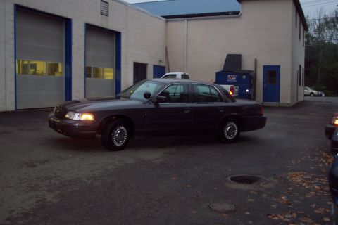 2001 Ford Crown Victoria - Dark 2001 Ford Crown Victoria sedan parked outdoors near a commercial building.