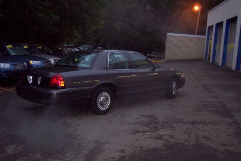 2001 Ford Crown Victoria - A dark gray 2001 Ford Crown Victoria is parked in a lot with other vehicles.