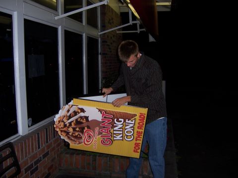 1991 Ford Bronco - Man carrying a large "GIANT KING CONE" advertisement outside a building at night.