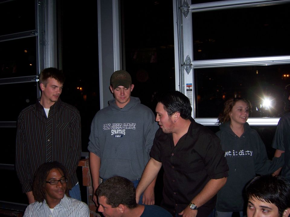 Group of people gathered indoors at night, with large garage-style doors in the background