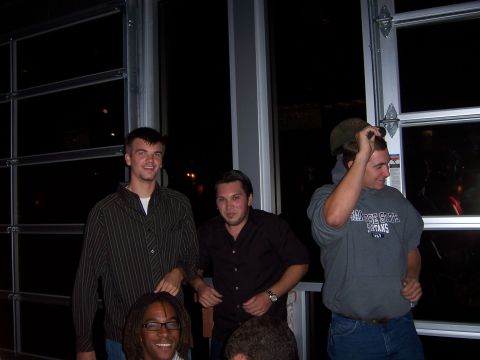 1991 Ford Bronco - A group of friends gathered indoors, with one man adjusting his hat.