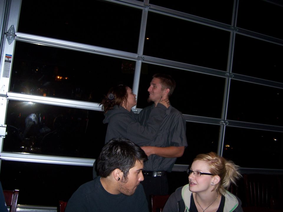 People gathered indoors with large windows reflecting a dark night