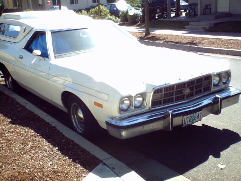 1973 Ford Ranchero - A white 1973 Ford Ranchero, equipped with a camper shell, is parked on a residential street.