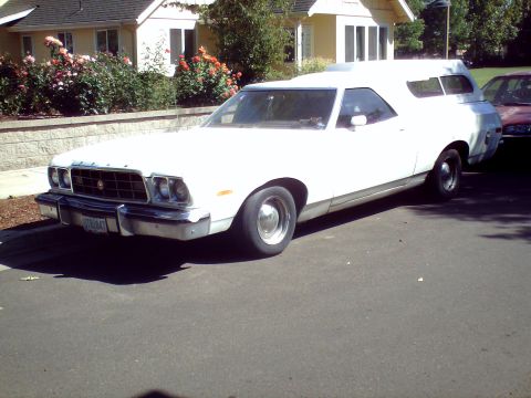 1973 Ford Ranchero - A white 1973 Ford Ranchero, equipped with a camper shell, is parked on a residential street next to another vehicle.
