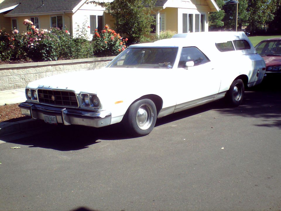 White 1973 Ford Ranchero with a camper shell, parked on a street, front 3/4 view