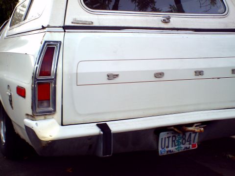 1973 Ford Ranchero - The rear of a white 1973 Ford Ranchero pickup truck is shown, a camper shell and a license plate.