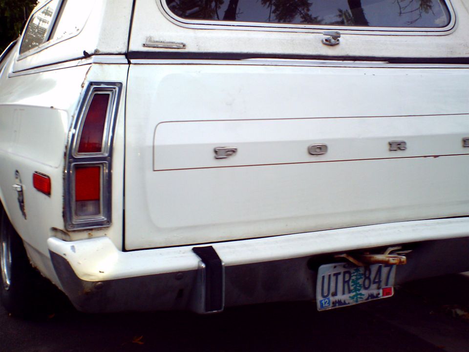 Rear of a white 1973 Ford Ranchero with a camper shell. License plate UTR 847 is visible