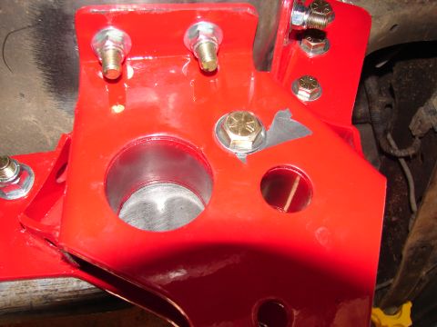 1996 Ford Bronco - Close-up of a red suspension part with bolts and openings, likely for a vehicle lift.