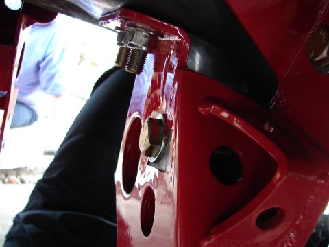 1996 Ford Bronco - Close-up view of a red painted metal bracket with visible bolts, with a person blurred in the background.