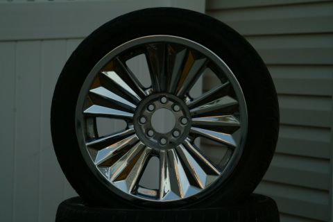 1999 Ford Crown Victoria - A shiny chrome wheel with a complex spoke design is shown, resting on another tire.